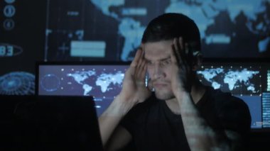 Genç adam geek hacker bilgisayar başında overworking ve Siber Güvenlik Merkezi göstermek perde ile dolu bir baş ağrısı muzdarip.