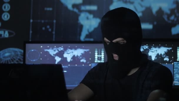 Gevaarlijke hacker in het masker probeert in te voeren van het systeem met behulp van codes en nummers om uit het beveiligingswachtwoord te vinden. Het concept van cybercriminaliteit. — Stockvideo