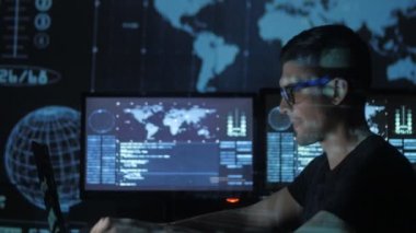 portre ile dolu veri merkezindeki bir bilgisayarda çalışan genç bir programcı görüntüleme ekranları