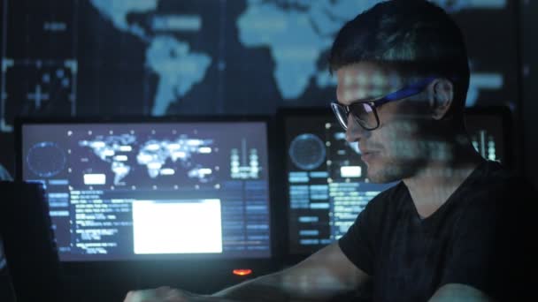 Retrato de un joven programador trabajando en una computadora en el centro de datos lleno de pantallas de visualización — Vídeos de Stock