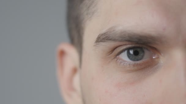 Graues Auge in Makro-4k-Aufnahmen eines jungen gutaussehenden Mannes — Stockvideo