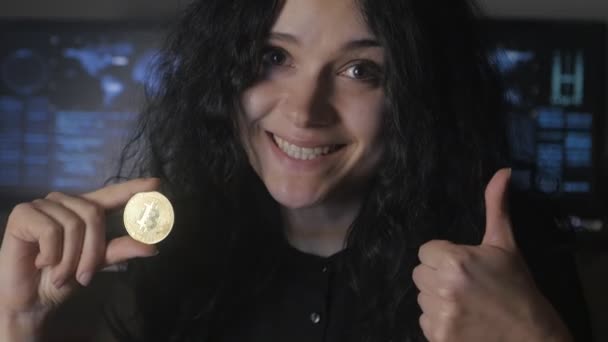 Mujer joven con el pelo rizado tiene Bitcoin oro en la mano. Minería y comercio — Vídeos de Stock