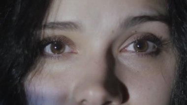 Bir video ya da Tv veya bilgisayar monitörü film izlerken bir genç kadının gözlerini kapatın. Yansıma yüzünde