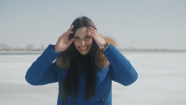 Портрет молодой довольно красивой брюнетки женщина улыбается на зимнем снежном фоне — стоковое видео