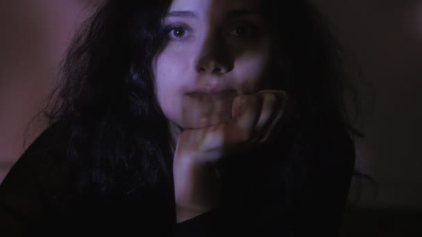 ビデオまたはテレビまたはコンピューター モニターのフィルムを見ている若い女性の肖像画を閉じます。彼女の顔に反射 — ストック動画