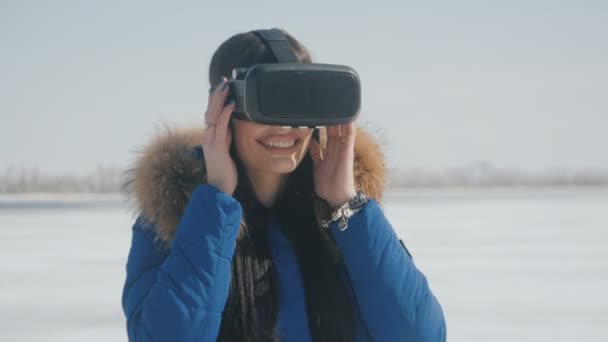 Retrato de una mujer joven que tiene experiencia en el uso de VR-auriculares al aire libre en invierno. Chica utiliza un casco de realidad virtual al aire libre — Vídeo de stock