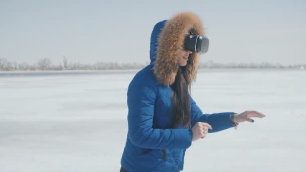 Retrato de mujer joven chaqueta azul obtener experiencia en el uso de VR-auriculares al aire libre en invierno. Chica utiliza un casco de realidad virtual al aire libre — Vídeos de Stock