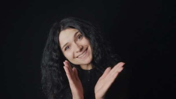 Retrato de mujer alegre con pelo rizado y ojos marrones aplaude y ríe de fondo negro — Vídeos de Stock