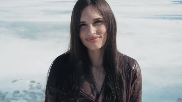 Retrato en cámara lenta de la joven hermosa morena en invierno sobre un fondo de nieve del río congelado — Vídeos de Stock