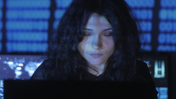 Portrait of young woman programmer working at a computer in the data center filled with display screens — Stock Video