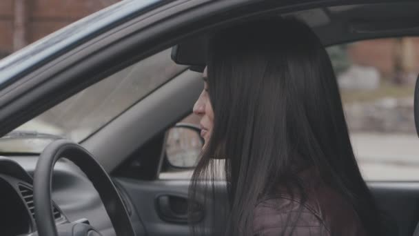 Веселая молодая женщина смеется, сидя в машине — стоковое видео