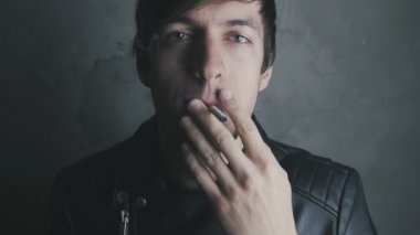 Deri ceketli genç adam sigara içiyor ve içecekler bira