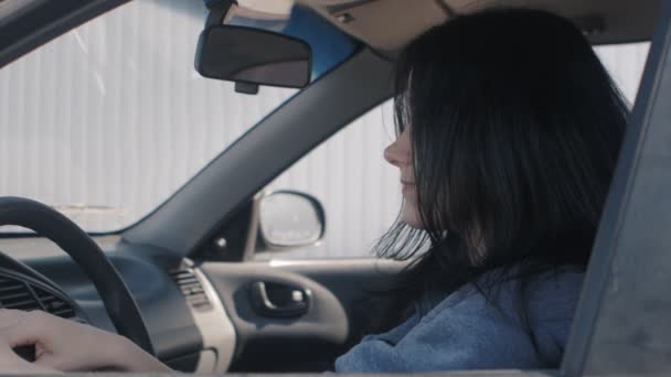 Bir araba sürücüleri koltuk direksiyonuna oturan, sevimli genç bir kadın portresi. — Stok video