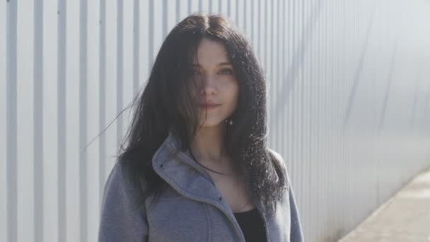 Portrét mladé ženy Černovlásky venkovní na ulici. Vítr snadno vlny její vlasy. — Stock video