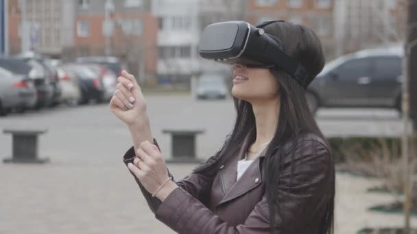 Jonge brunette vrouw krijgt ervaring in het gebruik van de Vr-headset of VR headset buiten op de straat van de stad — Stockvideo