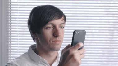 Panjur arka plan üzerinde Beyaz gömlekli genç bir adam portresi.