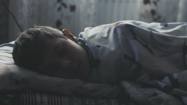 男孩晚上睡在床上, 在他的卧室, 覆盖着毯子. — 图库视频影像