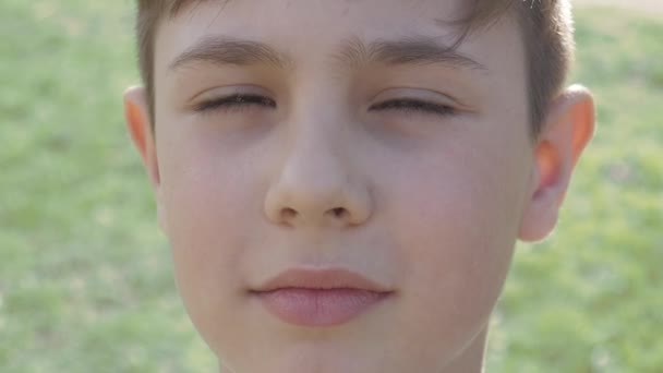 Primer retrato de un niño de 10 años sobre un fondo de vegetación en primavera o verano . — Vídeos de Stock