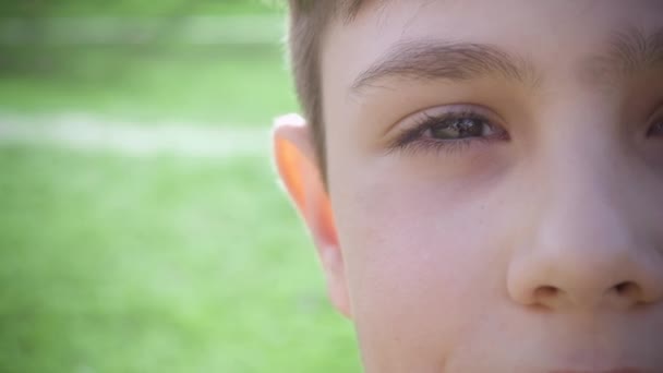 Close-up van portret half-gezicht van een jongen van 10 jaar oud op een achtergrond van groen in de lente of zomer. — Stockvideo