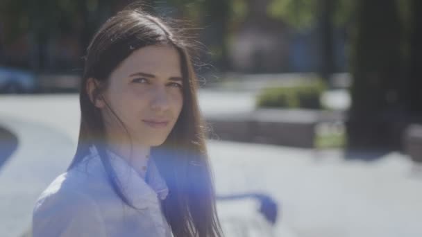 Beyaz gömlekli bir genç kadının portresi kadar güneşli bir şehir sokak kapatın — Stok video