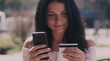 Çekici genç kadın kullanma online alışveriş cep telefonu ve internet bankacılığı sıcak yaz gününde açık ile ödeme