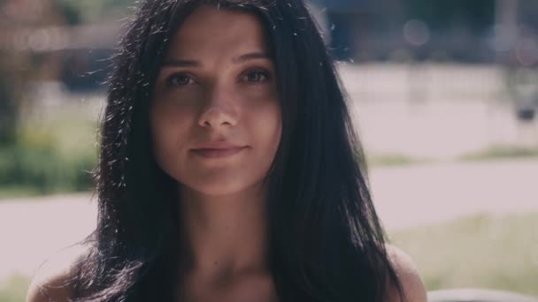 Porträt einer jungen brünetten Frau in einer Straße der Stadt, die in Zeitlupe in die Kamera blickt — Stockvideo