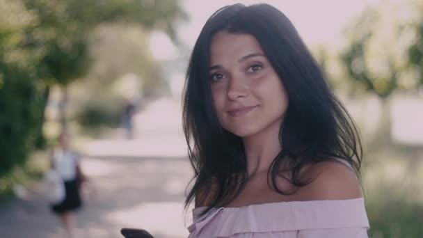 Hermosa joven en la calle de la ciudad y girando a la cámara y sonriendo. Movimiento lento — Vídeo de stock