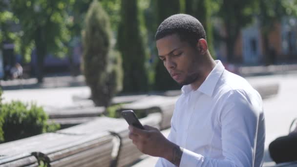 African American Man SMS mensajes de texto utilizando la aplicación en el teléfono inteligente en la ciudad. — Vídeo de stock