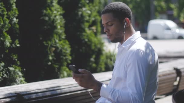 Afroamerikaner sendet SMS per App auf Smartphone in der Stadt. — Stockvideo