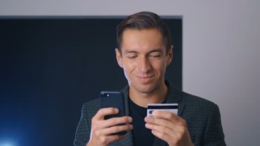 Genç iş adamı, ofisteki akıllı telefonu kullanarak online alışveriş yapıyor. Çevrimiçi bankacılık mobil uygulaması.