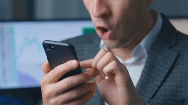 Akıllı telefonu kullanan heyecanlı bir adam internetten bahis oynayarak çok mutlu oluyor. Kumar oyunu kazanıyor. Telefona bakan mutlu işadamı zaferi kutluyor.