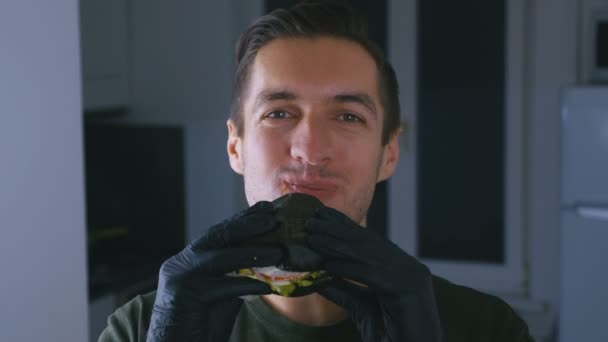 Young Man enjoing of eating a Black Burger. Fast food. Cheeseburger, hamburger, sandwich. — Stock Video