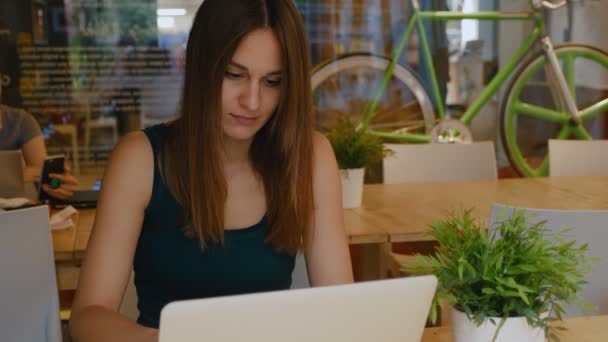 Mujer bonita joven trabaja en computadoras portátiles en una moderna oficina de coworking . — Vídeos de Stock