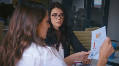 Ofiste iş birliği yapan iki kadın iş arkadaşı iş yerinde iş birliği yapıyor. İş kadınları iş arkadaşları şirket takım çalışmasında iş projesini tartışıyor.