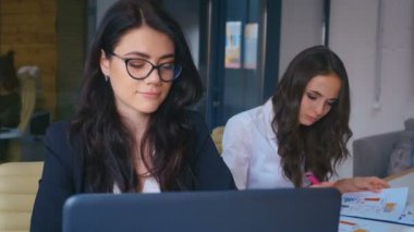 Modern Ofiste Dizüstü bilgisayarla çalışan Gözlüklü Çekici Genç İş Kadını