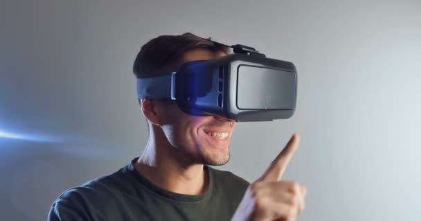 Anak muda memakai teknologi virtual reality VR Glasses. Pria yang terkejut dengan adanya augmented reality dalam helm virtual reality dengan latar belakang putih — Stok Video