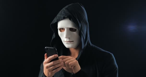 Un fraudeur anonyme masqué à la cagoule exige une rançon pour chantage à l'aide d'un smartphone. Masked Criminal intimide la victime à l'aide de menaces par SMS à l'aide d'un téléphone mobile . — Video