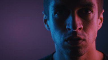Neon ışıklarda Siktir Seni Gösteren Adamın Portresi. Agresif ayarlı erkek neon ışık ile aydınlatılmış karanlık bir odada orta parmak gösterir.