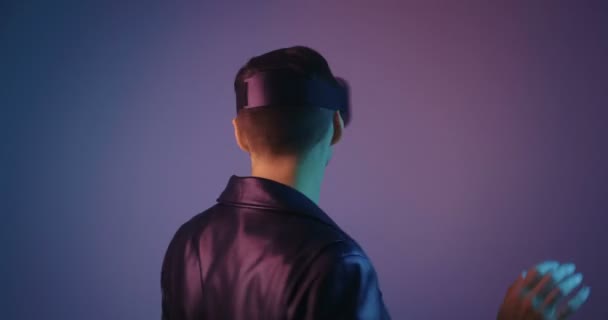 Retrato de varón usando VR Glassess en luz de neón multicolor. Hombre joven en casco de realidad virtual en luces de neón futuristas . — Vídeo de stock