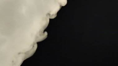 Gerçekçi Duman Bulutları çerçevenin içinden uçuyor. Efektler ve geçişler için iyi bir görüntü. Siyah izole arkaplanda duman bulutu