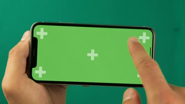 Gros plan des mains masculines touchant le smartphone. Écran vert Chroma Key. L'écran du téléphone est une clé chromatique verte, arrière-plan avec un autre écran vert chromatique. Images pour les annonces mobiles, app promo . — Video