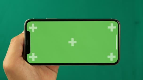 Smartphone horizontal na mão closeup isolado em fundo verde. Tela do telefone é chave de croma verde, fundo com outra tela verde chave de croma. Filmagem para anúncios móveis, app promo . — Vídeo de Stock