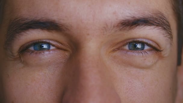 Primer plano macro hermosos machos ojos azules. El hombre entrecierra los ojos . — Vídeos de Stock