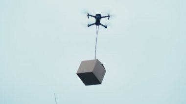 Bir insansız hava aracının yardımıyla geleceğin mallarının teslimatı. Büyük kahverengi paketi uçuran çoklu helikopter..