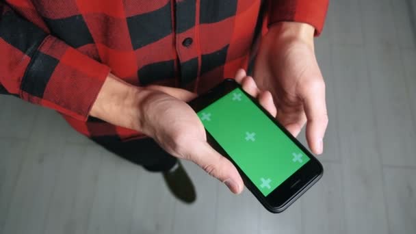 乌克兰基辅- 2019年11月28日：站立者使用手机绿色屏风室内。 持智能手机绿色屏幕彩色键的男性 — 图库视频影像