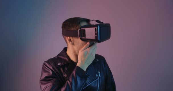 Primer plano del macho usando VR Glassess en luz de neón multicolor. Retrato de un joven en casco de realidad virtual con luces de neón futuristas . — Vídeos de Stock