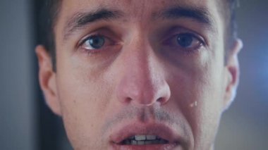 Depresyonda olan adam ağlıyor, yanağından gözyaşları akıyor, yakın plan.