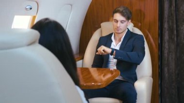 Özel Jet uçağıyla gelen yakışıklı zengin adam. Takım Elbiseli Genç İş Adamı Business Class Airplane 'da Ağaçlanıyor. Klasik Takım Elbise Giymek.