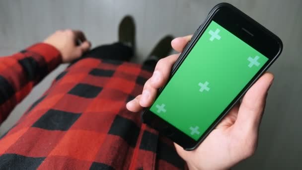 우크라이나 키 에프 - 2019 년 11 월 28 일: 휴대 전화그린 스크린 실내에서 서 있는 남자. 스마트폰 녹색 스크린 크로마 키를 들고 있는 남성 손 — 비디오