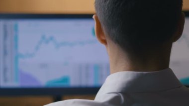 İşadamı bilgisayarda çalışıyor, dikiz aynasından. Erkek borsacı piyasadaki hisse senedi satış istatistiklerine bakıyor.